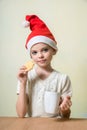 ÃÂ¡ute girl in Santa Claus hat eat cookies.